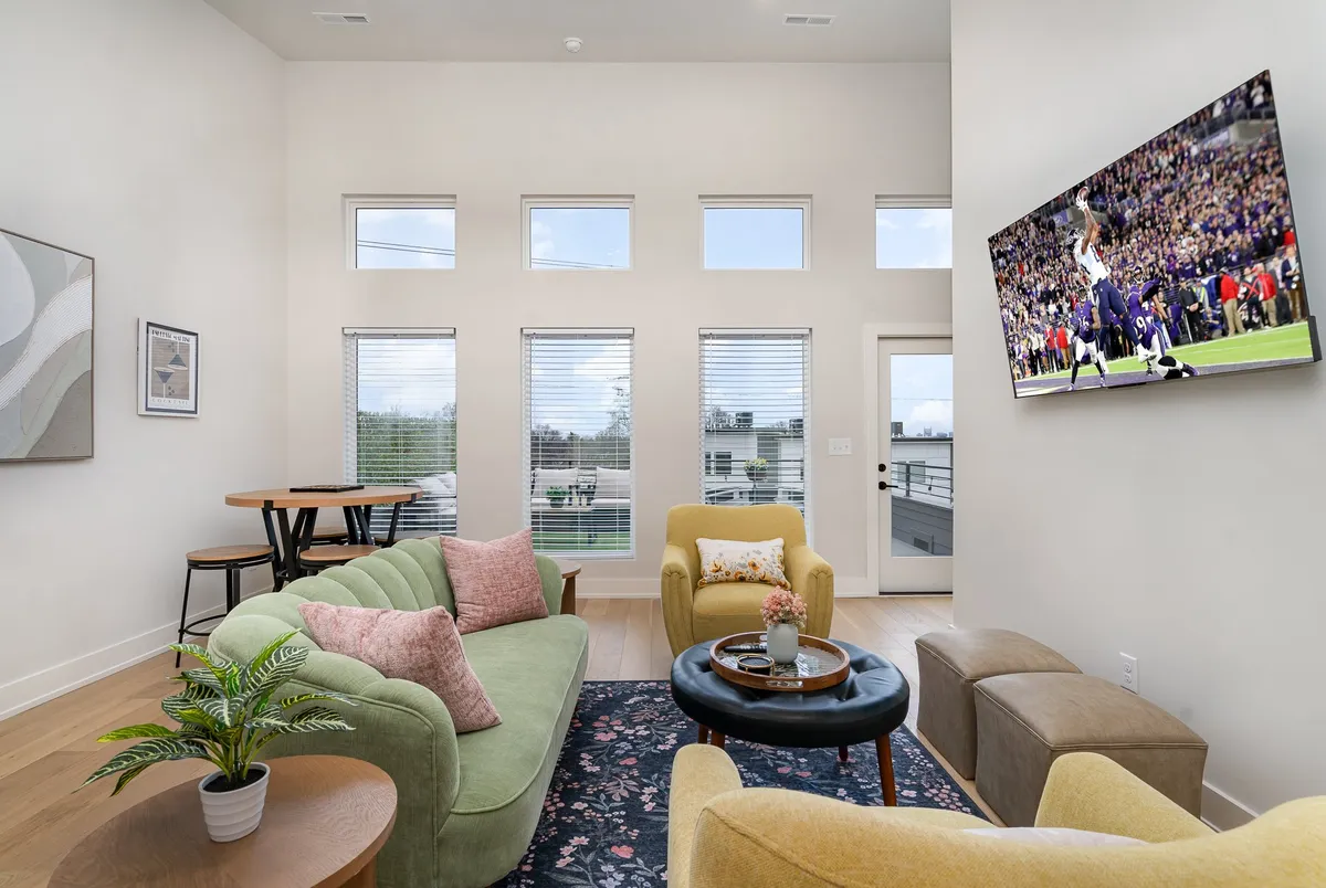 This image features a green sofa set in a vibrant living area, with a wall-mounted TV displaying a sports game, decorative plants, and a round coffee table. The mood is casual and vibrant, suggesting a space perfect for both relaxation and entertaining guests.