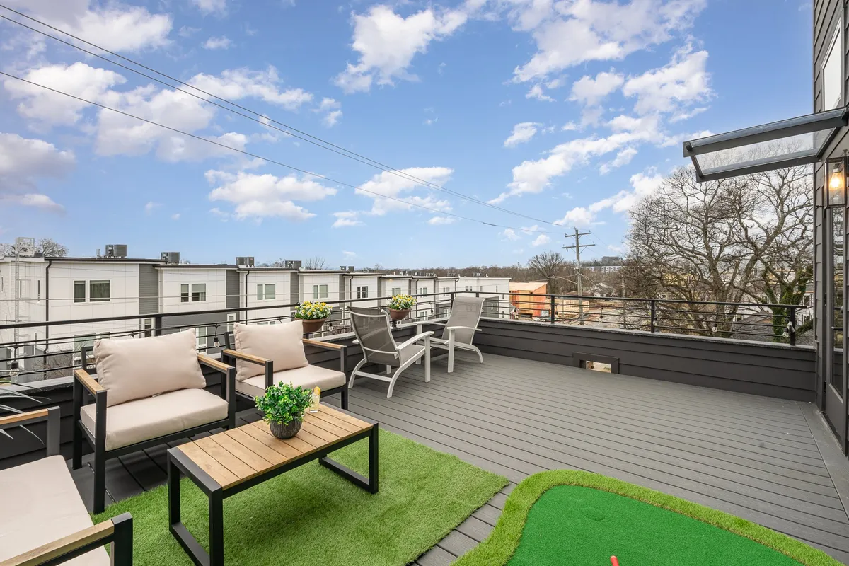 A rooftop deck set up with an outdoor seating area, putting green, and decorative planters. The scene conveys a relaxed, sociable mood perfect for gatherings or enjoying the view.